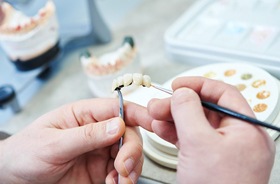 close-up of dental lab technician’s hands working on prosthetic teeth