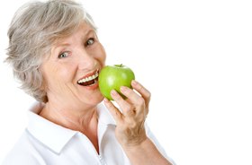 Senior woman enjoying apple with help of dental implants