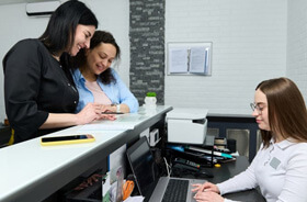 Patient standing at dental office front desk, paying for treatment