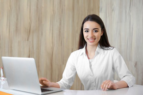 Friendly dental team member sitting behind desk
