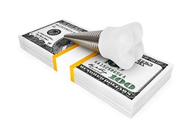 Model implant and money stack representing cost of dental implants in Auburn