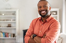 Confident man with dental implants in Auburn smiling inside his home