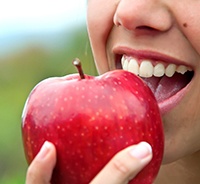 Closeup of woman with dental implants in Auburn eating an apple