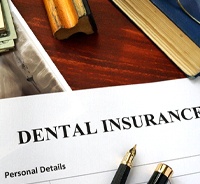 Dental insurance form next to glasses, money, and X-Ray