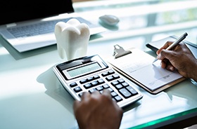Using calculator and pen to budget for dental care