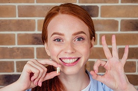 Patient making OK sign while holding extracted tooth