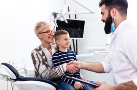 mother and young son happily greeting dentist in treatment room