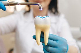 Dental team member demonstrating how curing light hardens dental filling