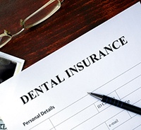 Dental insurance form on table next to glasses and X-Ray