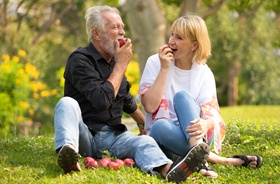 Couple enjoying apples with help of implant dentures