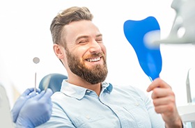 Dental patient using mirror to admire his new restorations 