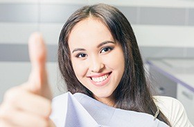 Smiling woman in dental chair giving thumbs up