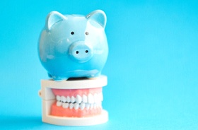 Piggy bank on top of teeth against blue background