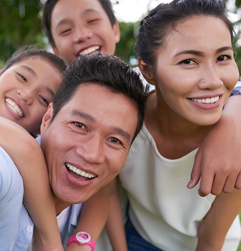Mother father and two children smiling outdoors