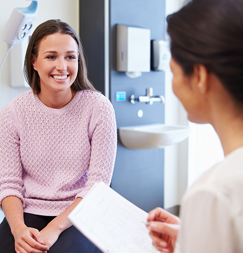Woman in pink sweater talking to dentist