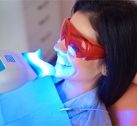Woman smiling during in-office teeth whitening treatment