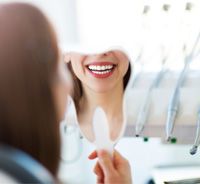 Patient smiling in mirror after whitening treatment