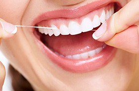 Woman flossing teeth to prevent new dental stains