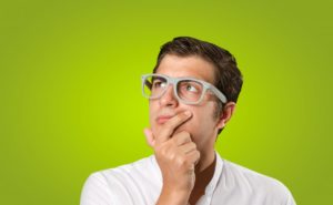 Portrait of man against green background, wondering about maintaining veneers