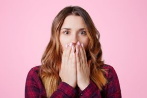 Woman covering mouth, concerned about the dangers of DIY whitening in Auburn