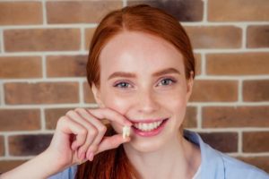 Smiling woman holding extracted tooth