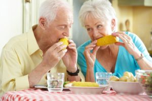Senior couple eating corn on the cob with dental implants