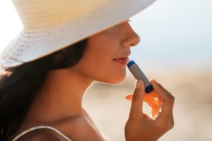 Woman wearing sunhat, applying SPF lip balm