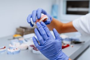 Gloved hands holding denture for upper dental arch