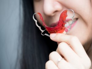 Smiling woman holding orthodontic retainer