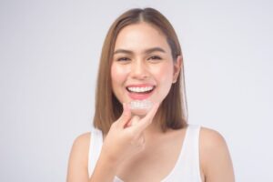 Smiling young woman holding clear aligner