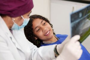 Teen girl looking at X-ray with her dentist 