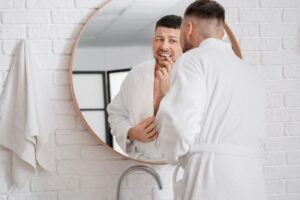 Concerned man looking at his gums in bathroom mirror 
