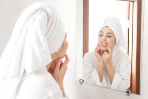 Concerned woman looking at her gums in bathroom mirror 