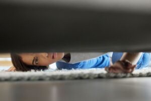 Woman looking under couch, searching for lost Invisalign aligner