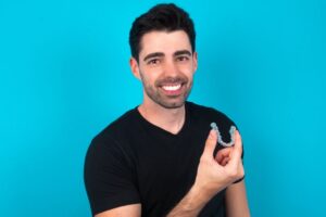 Happy man holding Invisalign aligner