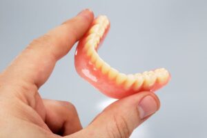 Close-up of a hand holding a lower denture 